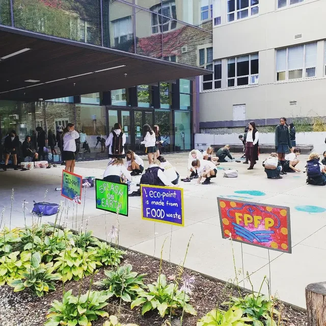 Students creating eco-paint murals outside a school